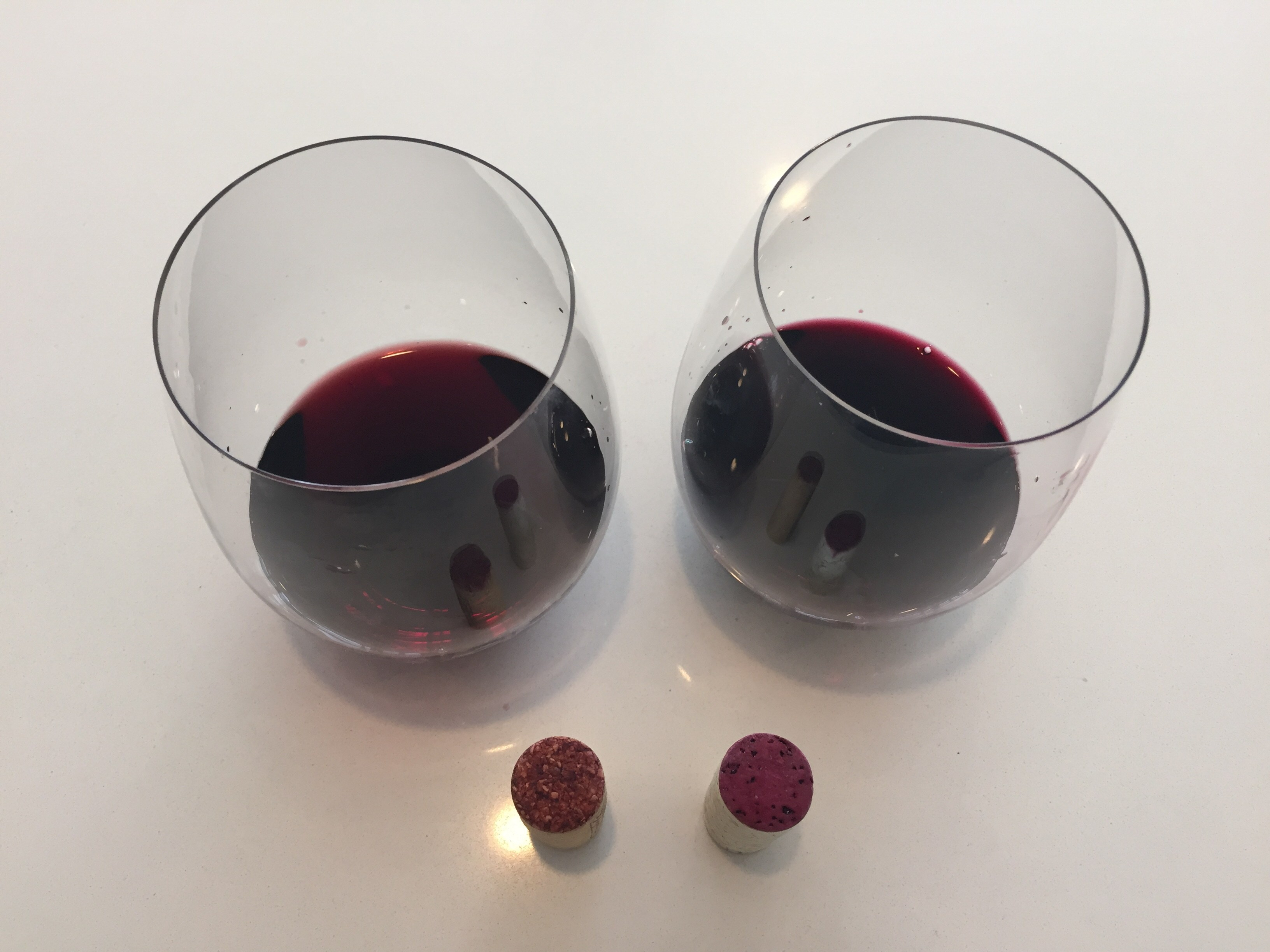 A glass of the brick red 2016 Kirkland Signature on the left, and a glass of the electric red/purple 2017 TJ's Reserve on the right.