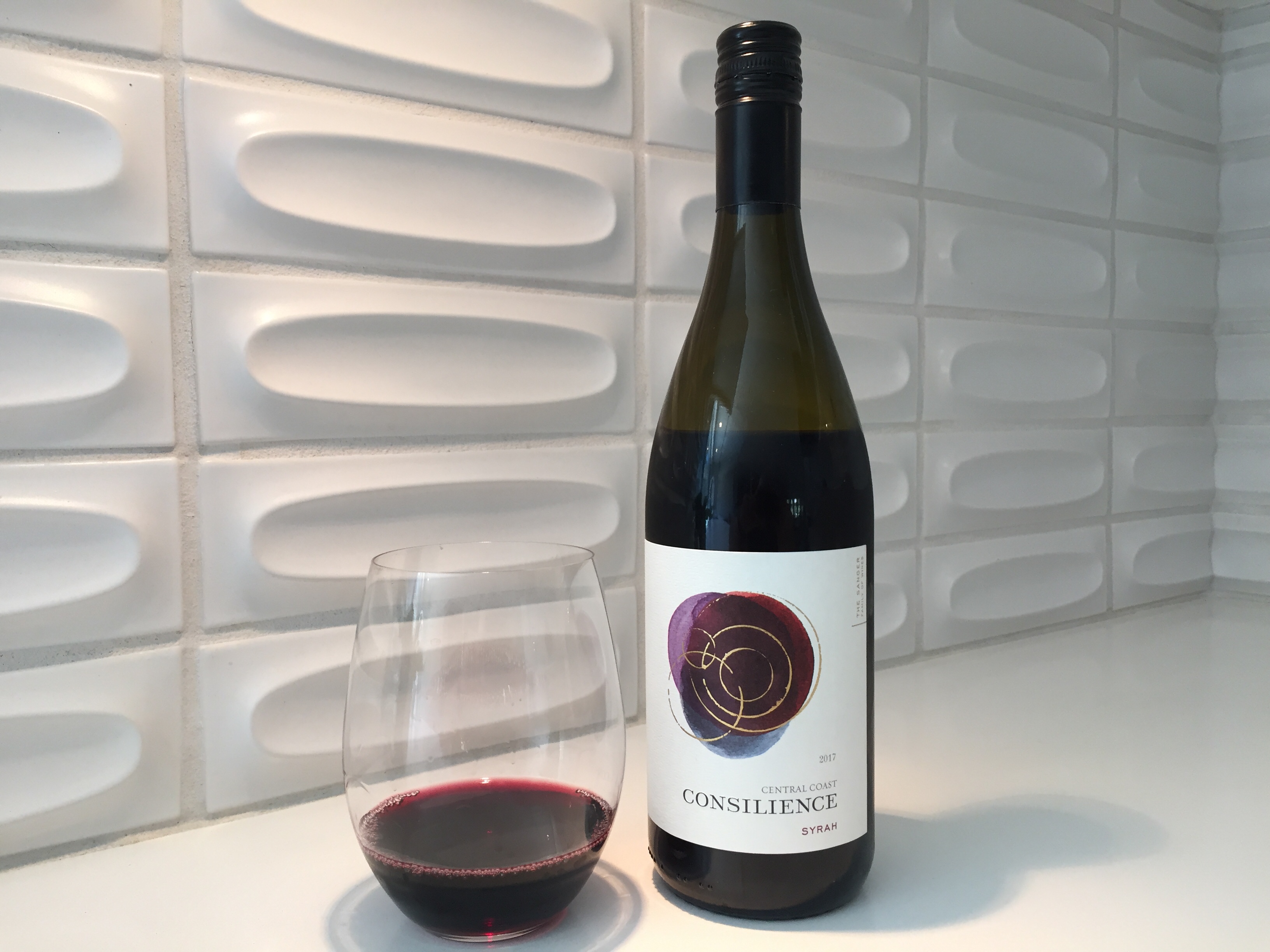 Bottle and glass of Consilience 2017 Syrah