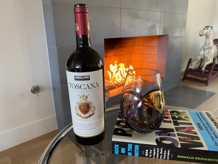 Bottle and glass of Kirkland Signature 2018 Toscana in front of a fire. $14.99 at Costco.
