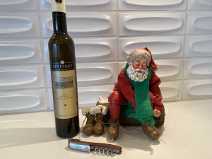 Bottle of 2019 Levesque Estates ice wine alongside a statuette of Santa Claus lacing up his ice skates.