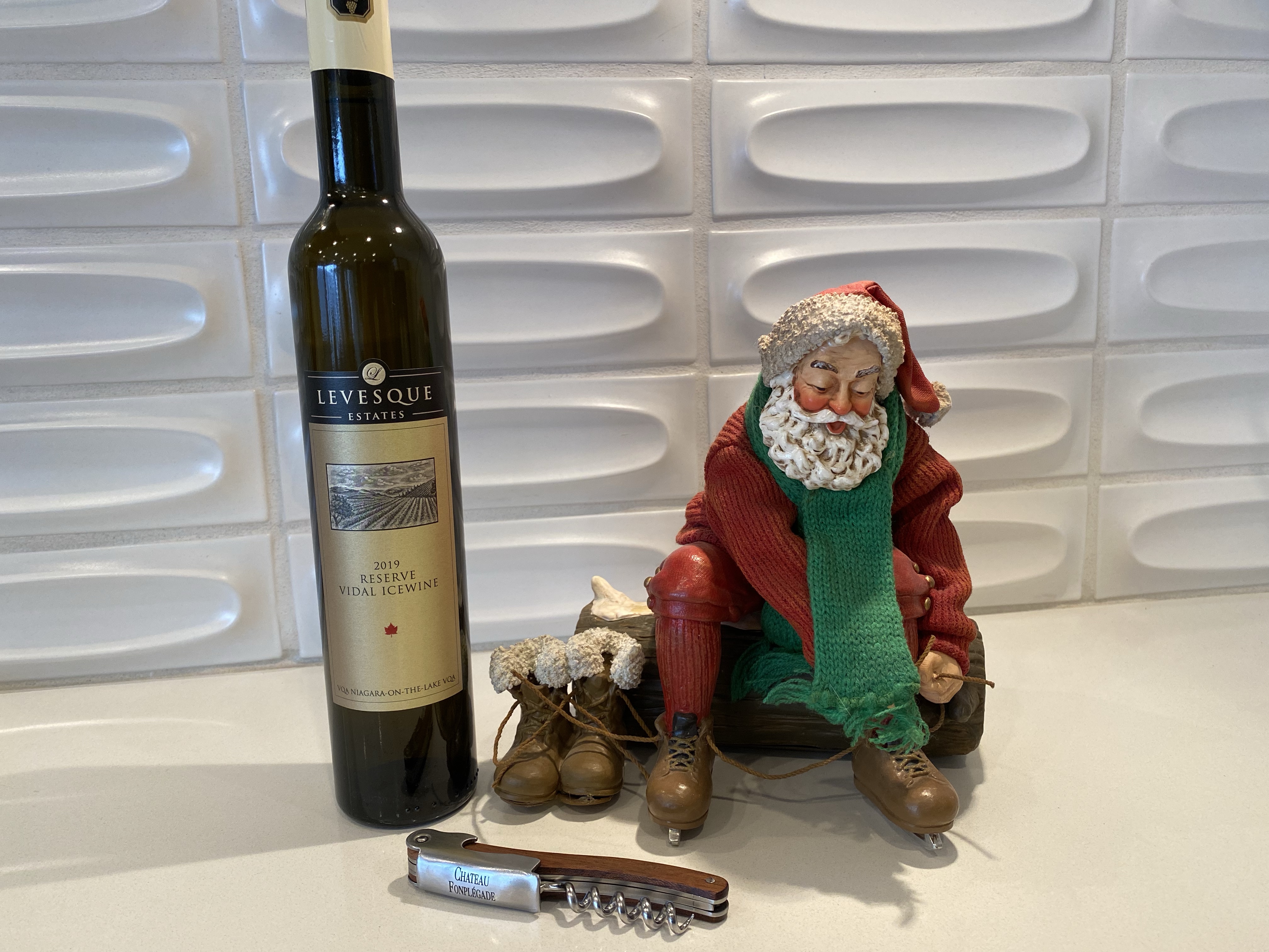 Bottle of 2019 Levesque Estates ice wine alongside a statuette of Santa Claus lacing up his ice skates.