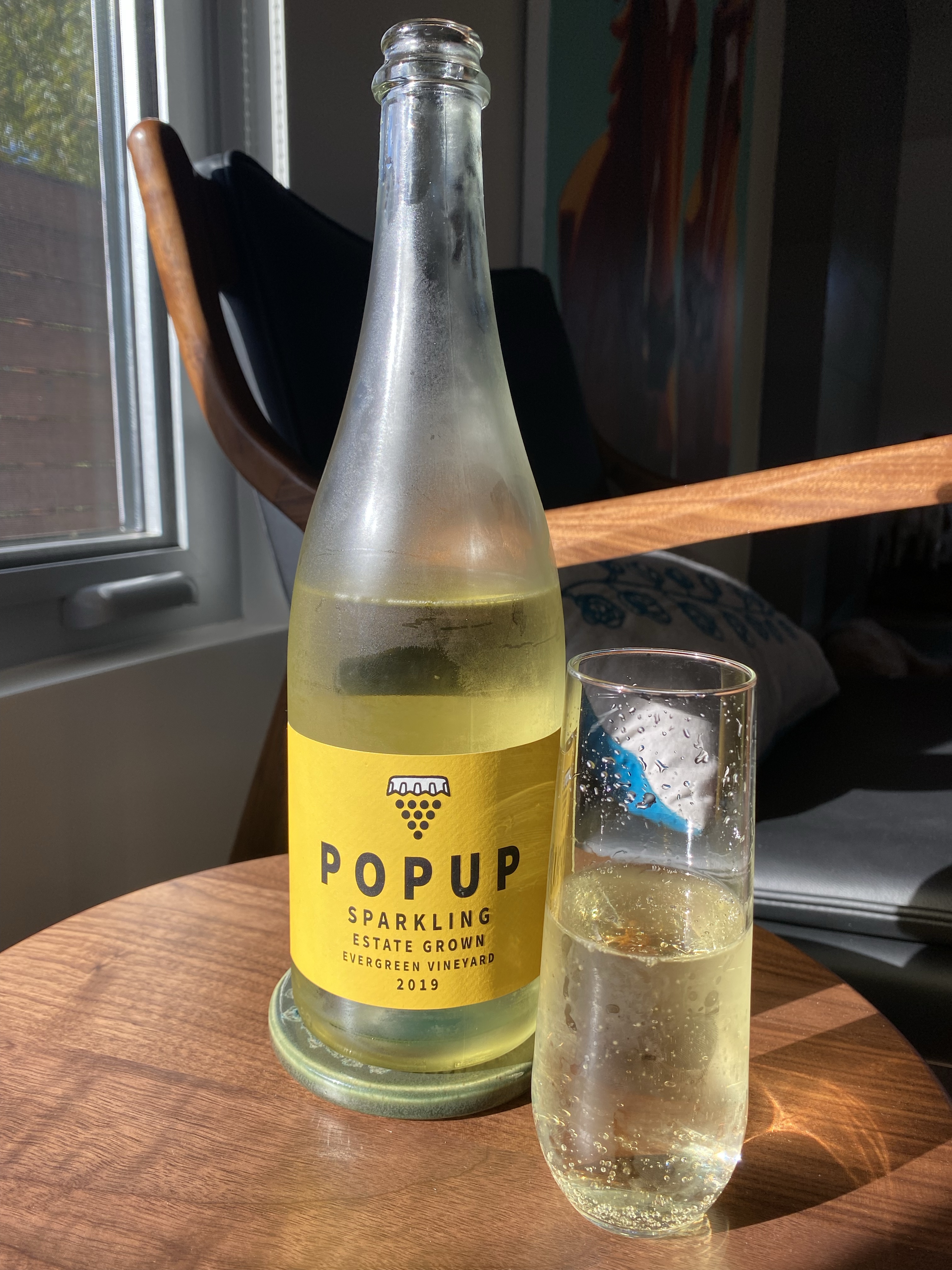 Glass and bottle of the 2019 Pop Up Sparkling, 100% Chardonnay, Evergreen Vineyard, Columbia Valley, Washington